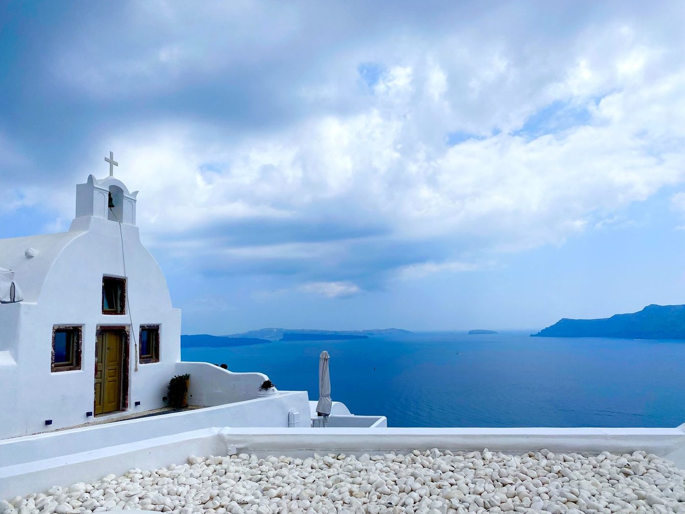 A whitewashed chapel with a cross overlooking the sea in Santorini
