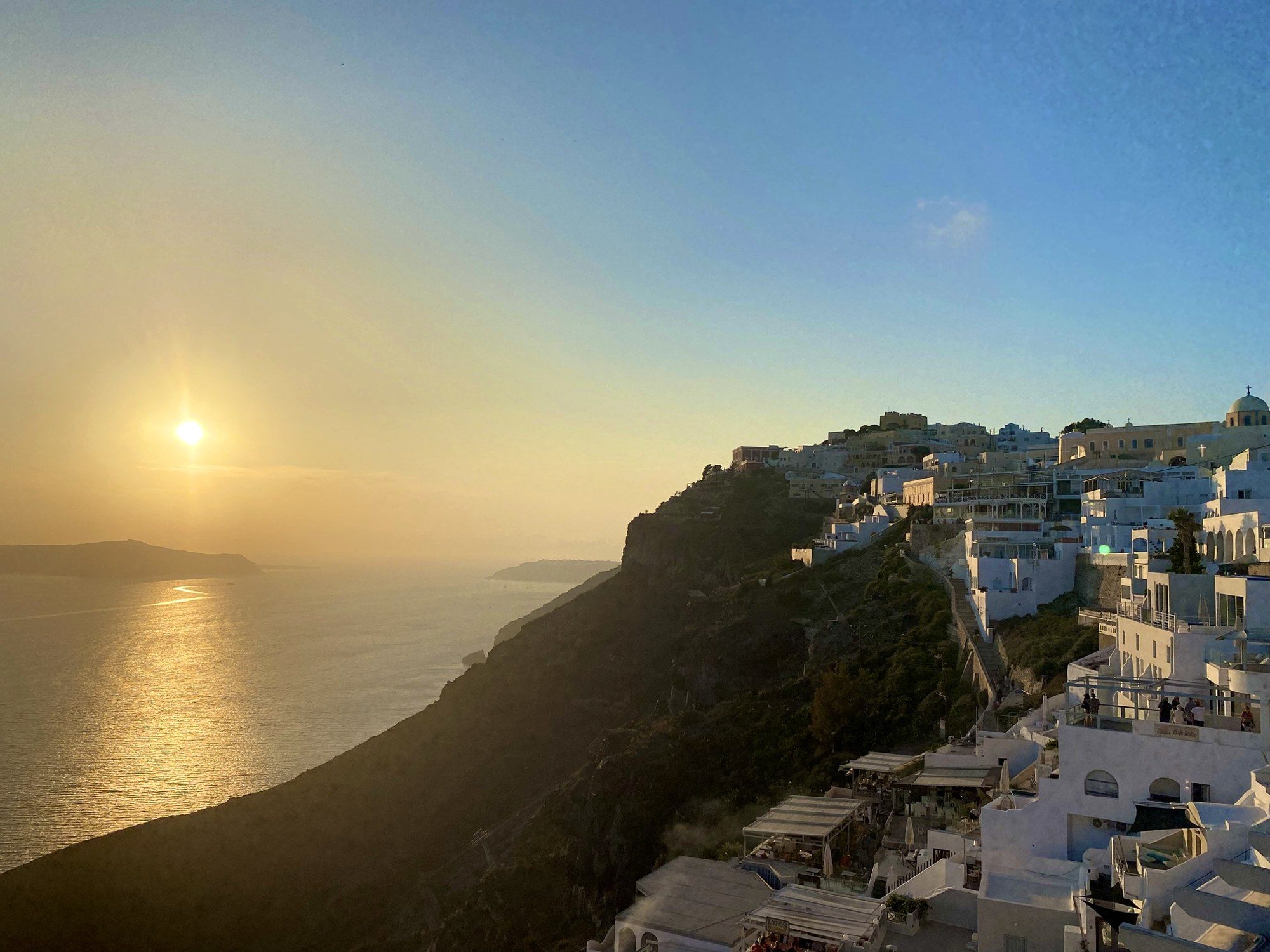 Golden sunset over the cliffs and white villages of Santorini